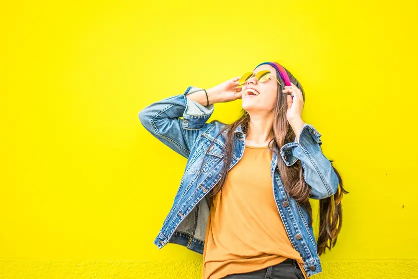 smiling-woman-looking-upright-standing-against-yellow-wall-1536619