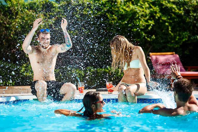 Young cheerful friends smiling, laughing, relaxing, swimming in pool. Copy space