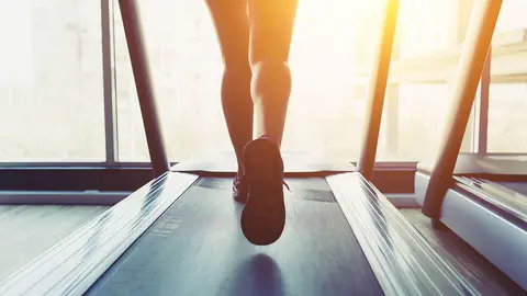 Fitness girl running on treadmill. Woman with muscular legs in gym