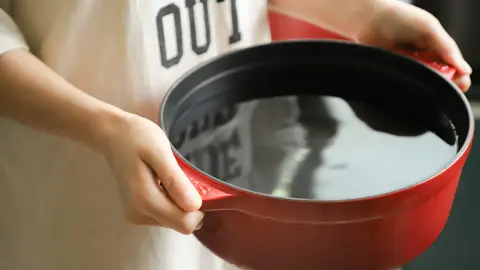 person-holding-red-pot-filled-with-water-1204251
