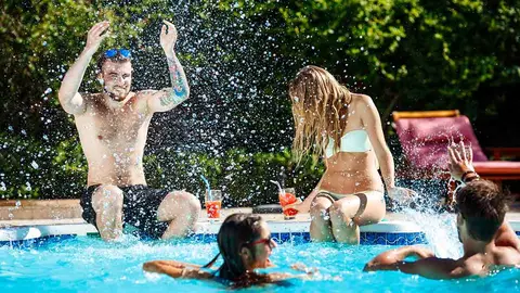 Young cheerful friends smiling, laughing, relaxing, swimming in pool. Copy space